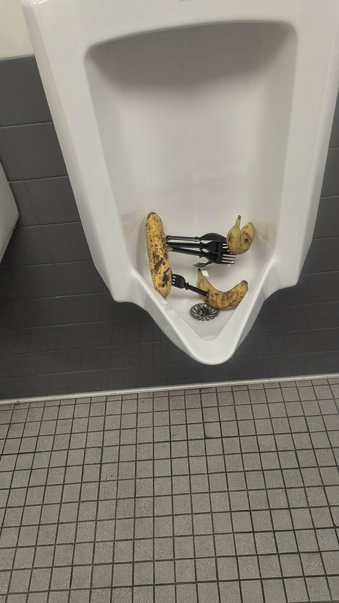 Urinal with scattered bananas and utensils, depicting an unusual and mundane setting.