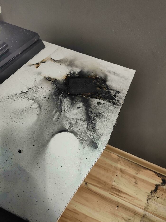 A scorched tabletop with dark burn marks, seemingly uninteresting yet intriguing in detail.