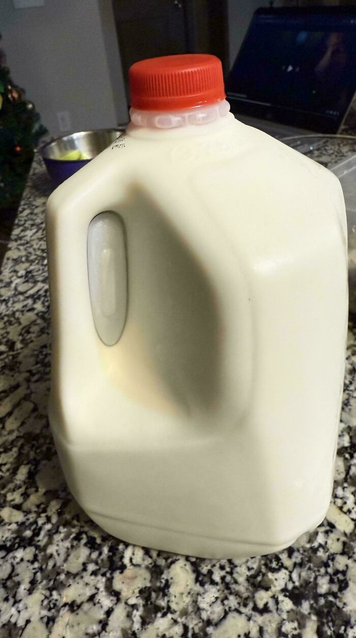 Plastic milk jug with a red cap on a granite countertop, representing uninteresting daily objects.