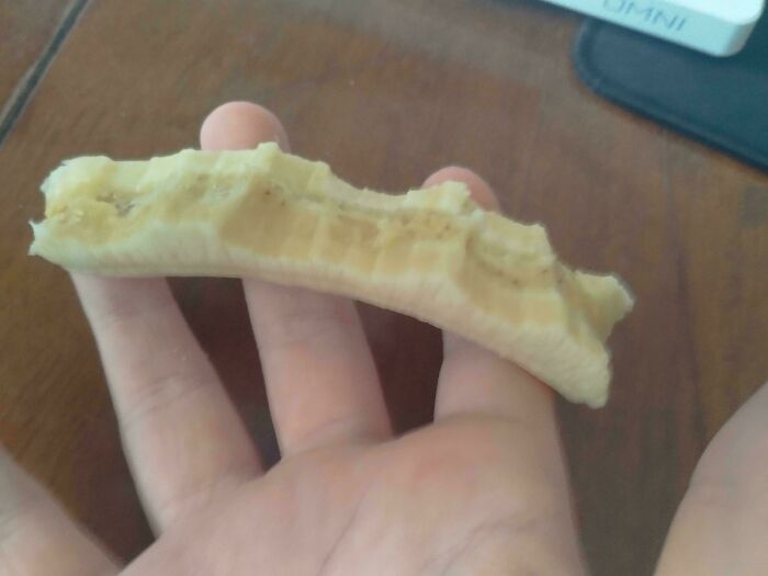 Unpeeled banana resting on a person's hand, showcasing its simple, ordinary nature.