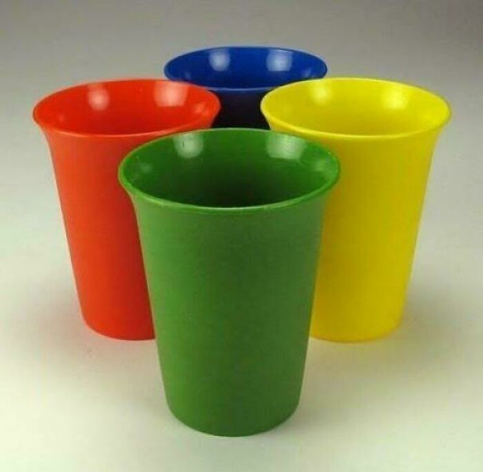 Set of four colorful nostalgic plastic cups in red, green, yellow, and blue, evoking memories from people realizing they’re old.