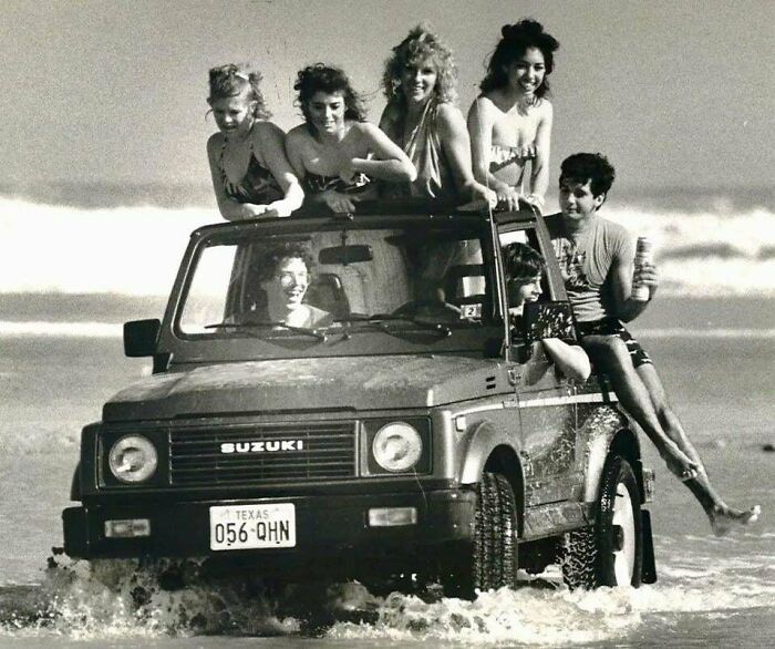 Group of friends enjoying a candid moment on a Suzuki vehicle driving through water, capturing glimpses into the past.