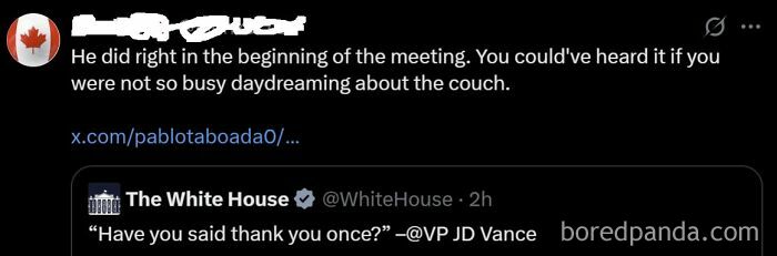 Man in a suit with a red tie sitting on a sofa, gesturing during a discussion.