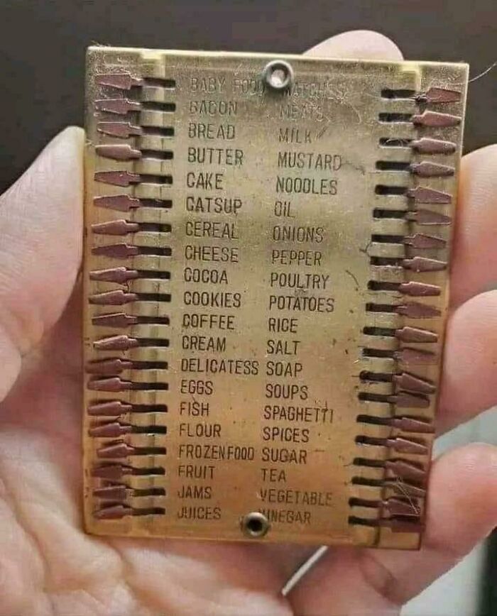 Hand holding a vintage grocery list tracker with metal sliders, illustrating ridiculous past shopping tools.