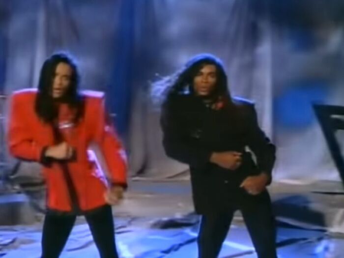 Two performers with long hair on stage, wearing bold red and black jackets during a scandalous awards show moment.