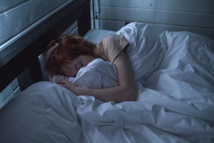 Person sleeping peacefully in a cozy bed, covered with white blankets.