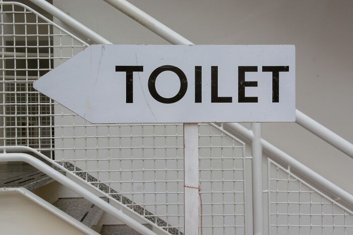 Sign pointing towards the toilet, representing simplicity amidst common office expressions hated by Redditors.