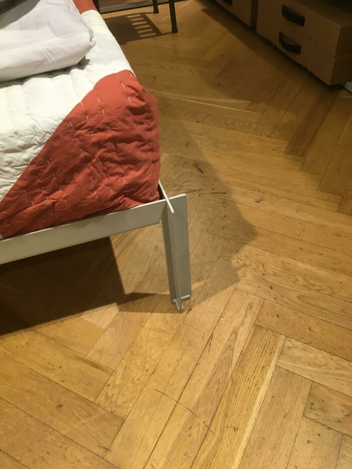 Bed with a broken frame in a room, showcasing a disastrous design flaw on wooden flooring.