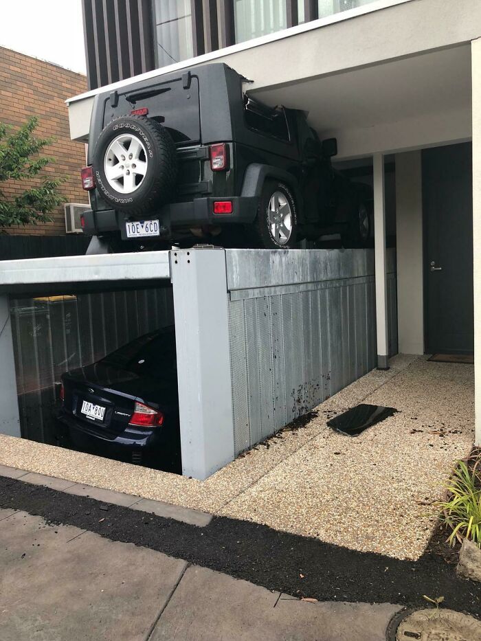 A car parked on top of another in a garage, showcasing a disastrous design choice.