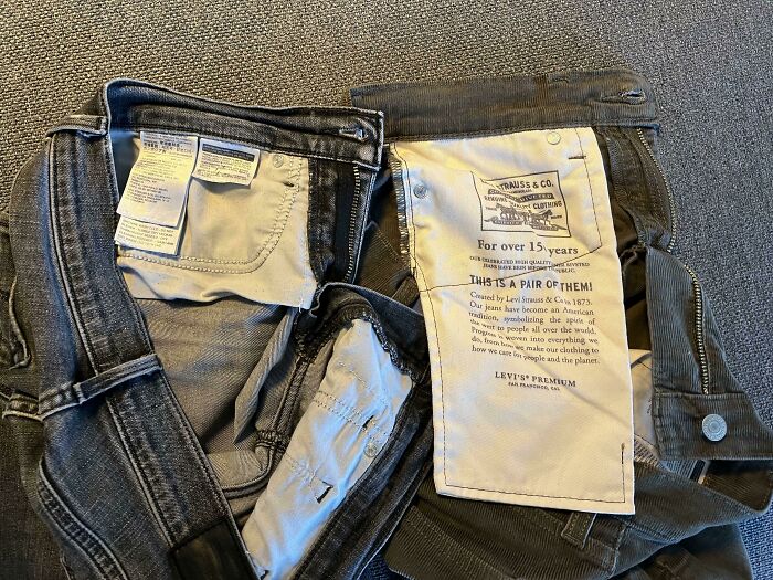 Open jeans with an oversized label on the inside, showcasing disastrous design elements.