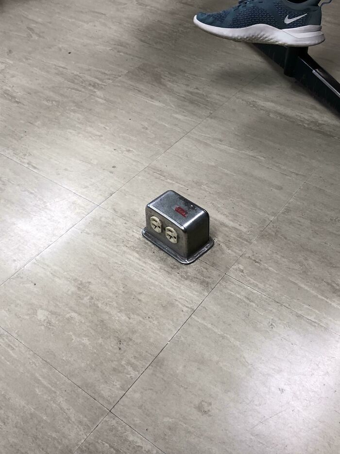 Floor outlet box awkwardly placed in the middle of a room, showcasing a disastrous design.