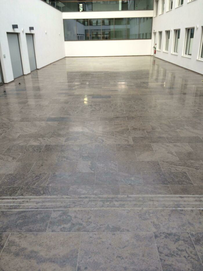Empty indoor space with a polished stone floor, showcasing a disastrous design choice in a large building.