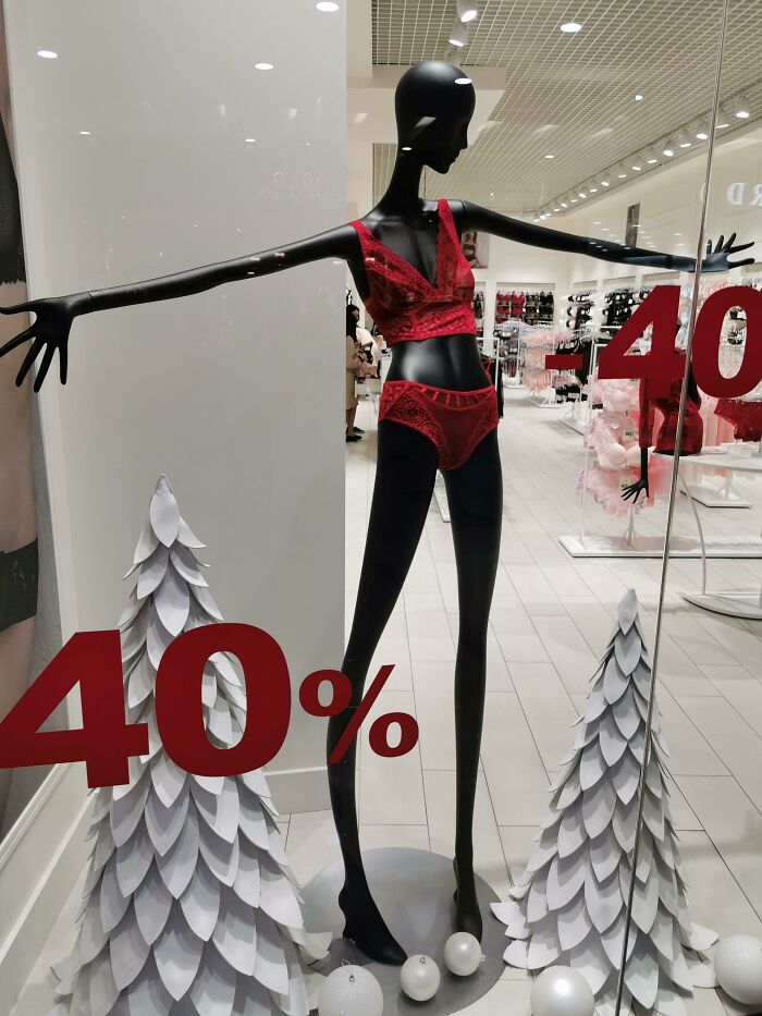 Mannequin in red lingerie with bold 40% discount sign, surrounded by white paper trees. Disastrous design display.