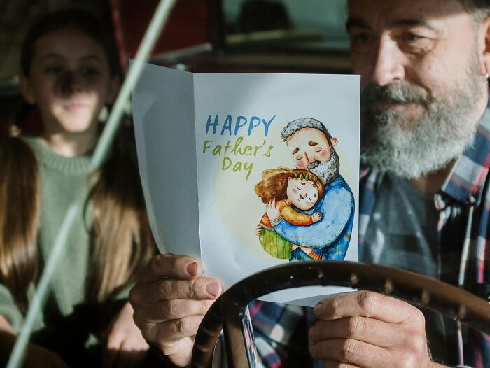 Bearded man holding a Father's Day card, challenging stereotypes about fatherhood in a touching moment.
