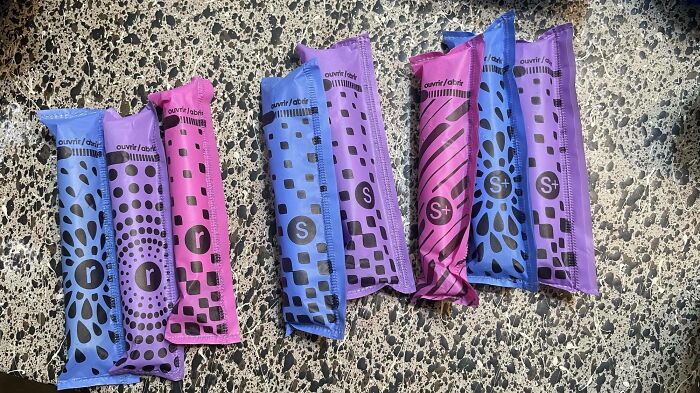 Colorful tampon packs with confusing design patterns displayed on a tiled surface.