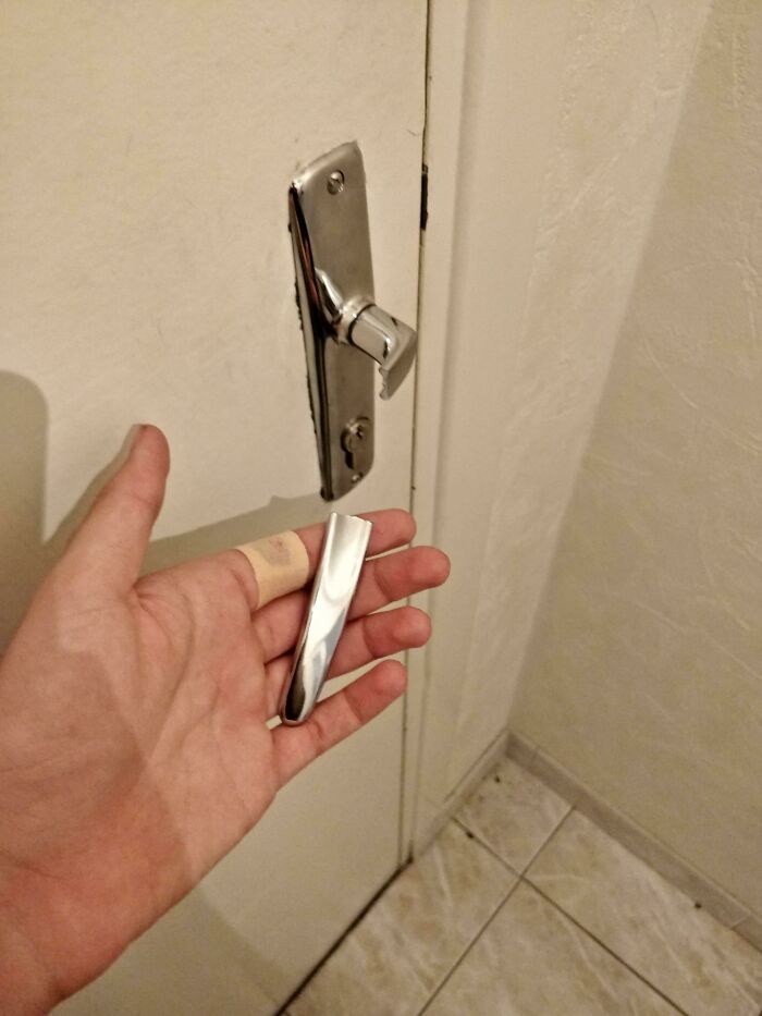 A broken door handle in hand, illustrating poor decisions impacting house functionality.