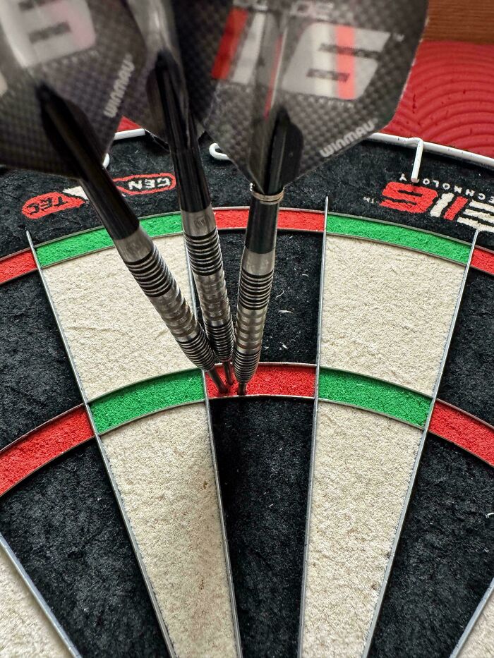 Darts perfectly aligned on a dartboard, landing in the bullseye, showcasing precision and focus.