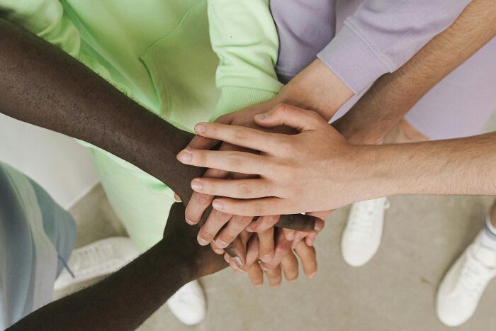Diverse hands stacked together in solidarity, symbolizing internet users uniting against stereotypes.