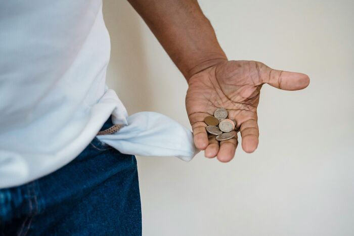 A person with an empty pocket holding coins, challenges a common stereotype.