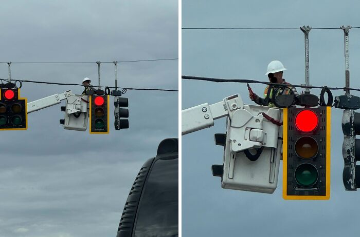 Worker repairing traffic lights at a high altitude, showcasing our world's fascinating aspects.