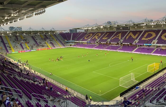 Modern soccer stadium with vibrant green field and purple seats, one of the iconic cathedrals of soccer worldwide.