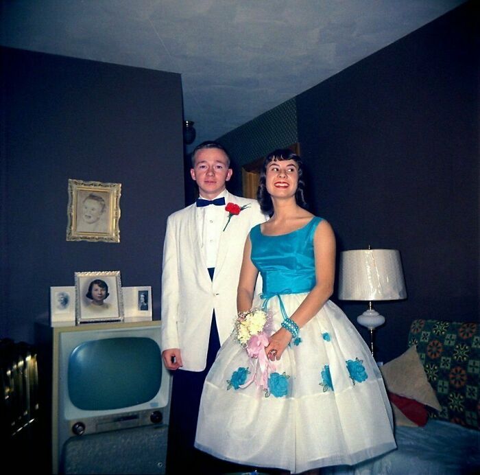 Teen couple in formal 1960s attire in a living room, reflecting America during the JFK years.