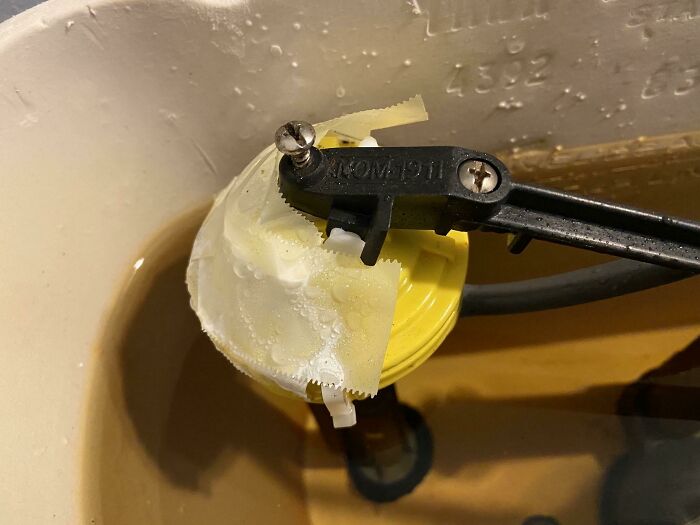 Toilet repair attempt with a plastic bag and zip tie, showcasing a failed repair attempt.