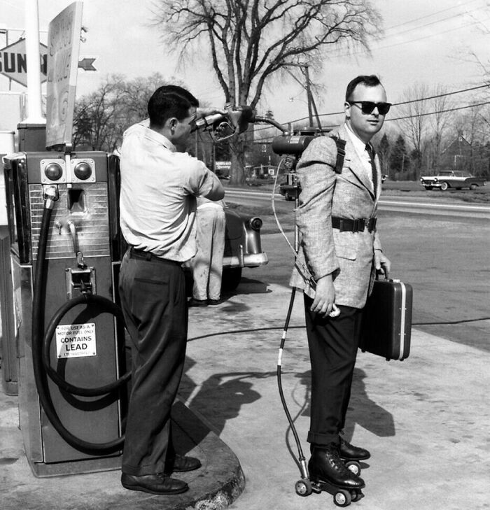 A man in a jetpack and roller skates being refueled at a gas station, showcasing 1960s America during the JFK era.