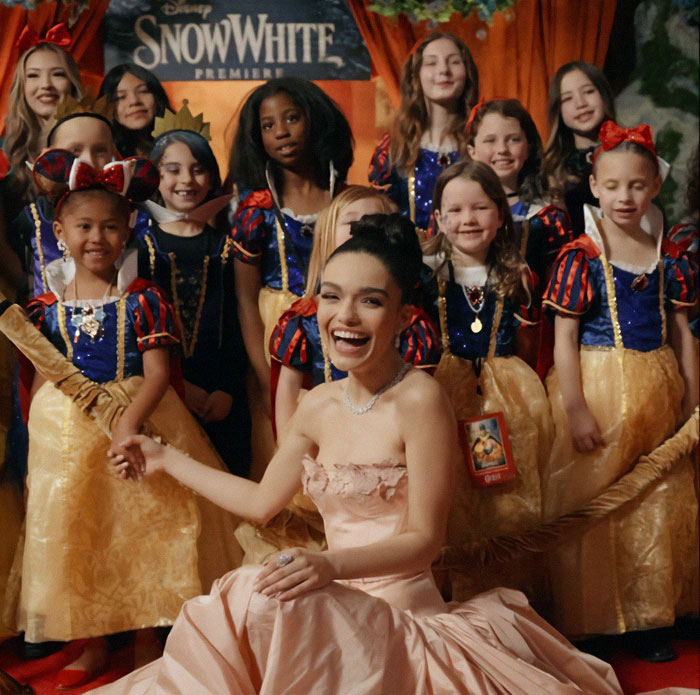 Smiling woman in a pink dress at 'Snow White' premiere with children dressed as characters. Smiling woman in a pink dress at 'Snow White' premiere with children dressed as characters.