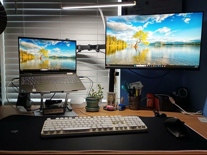Office desk setup with dual monitors, ergonomic keyboard, and decor for a productive workday environment.