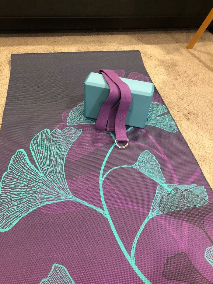 Yoga mat with a floral design, paired with a teal block and purple strap, symbolizing relaxation and digital detox.