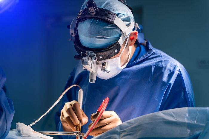 A surgeon in a blue gown performing a delicate operation, representing post-degree career paths.