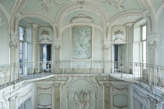 Elegant yet eerie hall in an abandoned place, featuring intricate moldings and faded frescoes.