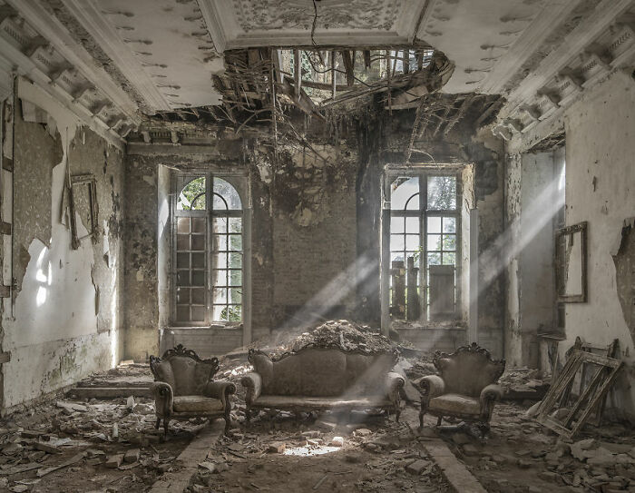 Abandoned place with decaying furniture, crumbling ceiling, and light streaming through broken windows.
