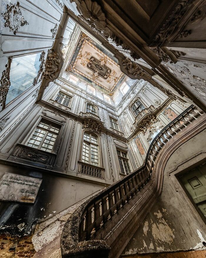 Abandoned place with grand staircase and ornate ceiling, showcasing eerie beauty and historical architecture.