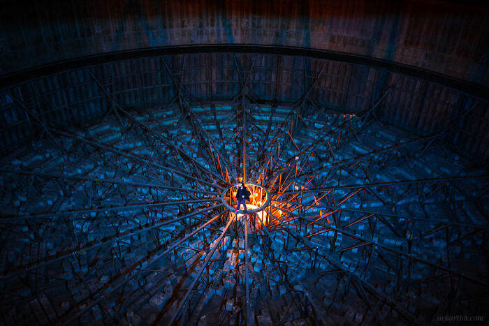 Abandoned place with a circular structure, eerie lighting highlights rusty beams in a desolate industrial setting.