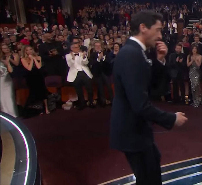 Adrien Brody during his Oscars speech, audience clapping, Cillian Murphy's look going viral in the background. Adrien Brody during his Oscars speech, audience clapping, Cillian Murphy's look going viral in the background.