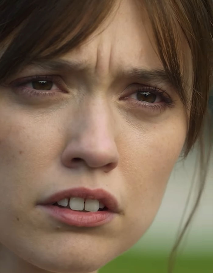 The White Lotus star with a serious expression, close-up focus on teeth. The White Lotus star with a serious expression, close-up focus on teeth.