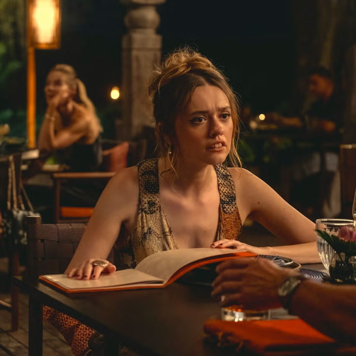 A person reading a menu at a restaurant table, engaged in conversation, with warm ambient lighting. A person reading a menu at a restaurant table, engaged in conversation, with warm ambient lighting.