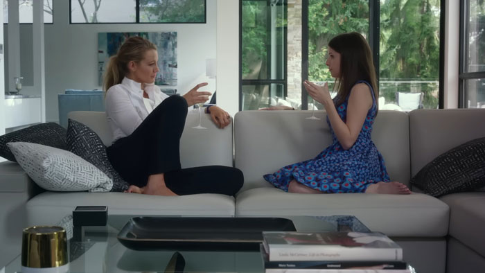 Two women sitting on a couch, engaging in a conversation, one in a blue dress, the other in white, part of Team Baldoni discussion. Two women sitting on a couch, engaging in a conversation, one in a blue dress, the other in white, part of Team Baldoni discussion.
