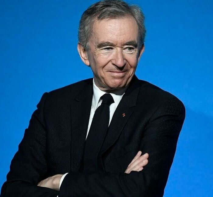 Portrait of a wealthy businessman in a black suit against blue background representing richest people with vast money.