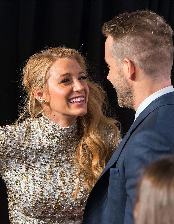 Blake Lively smiling in a sparkling dress on the red carpet, talking to a man in a suit, creating buzz. Blake Lively smiling in a sparkling dress on the red carpet, talking to a man in a suit, creating buzz.