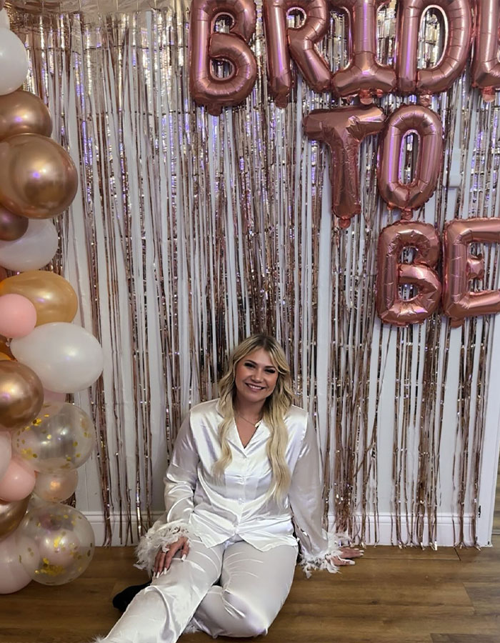 Bride-to-be at bachelorette party smiling in front of festive balloons and decorations. Bride-to-be at bachelorette party smiling in front of festive balloons and decorations.