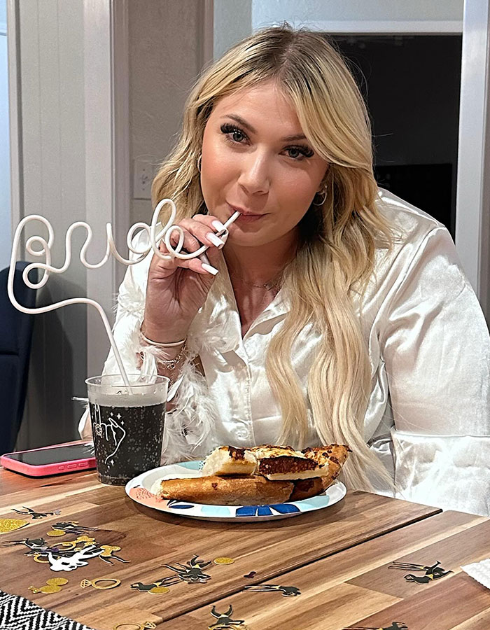 Bride-to-be enjoying pizza and drink with a straw labeled "bride" at a festive bachelorette party. Bride-to-be enjoying pizza and drink with a straw labeled "bride" at a festive bachelorette party.