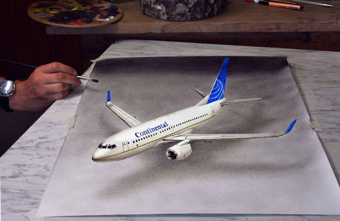 Artist's 3D drawing of an airplane, showcasing incredible realistic details with a brush on a tabletop.