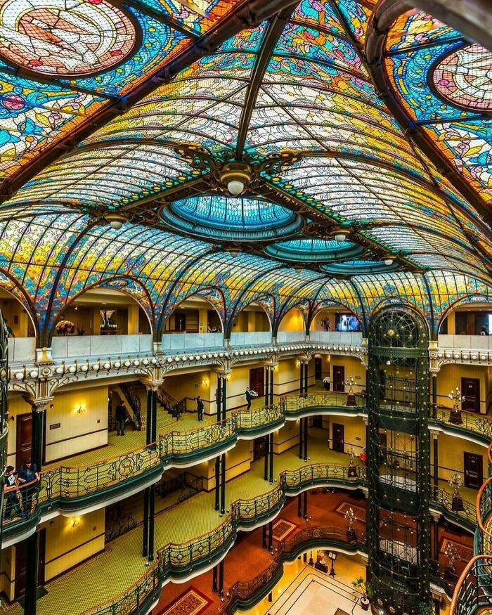 Stunning old American architecture with intricate stained glass ceiling and ornate iron balconies.