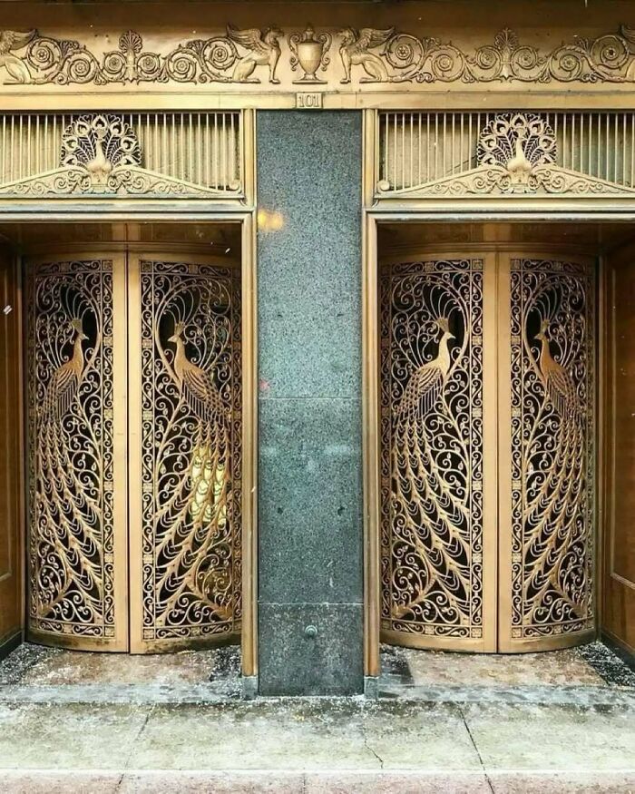 Ornate antique elevator doors with intricate peacock designs in old American architecture style.