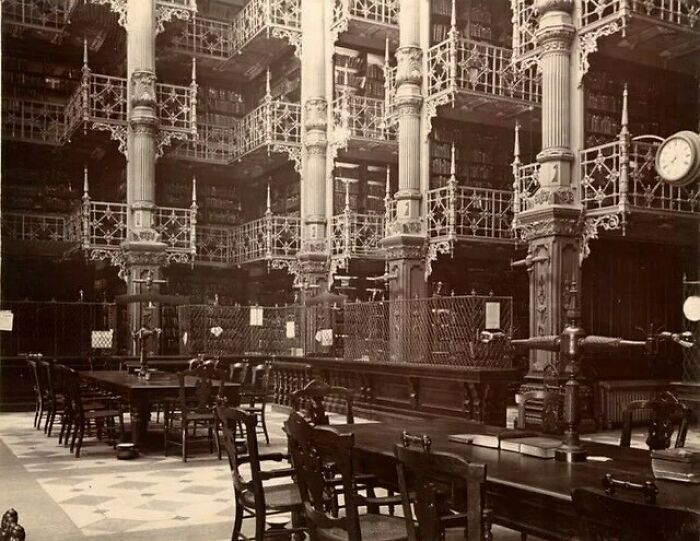 Vintage American architecture with ornate ironwork and wooden tables in a grand library interior.