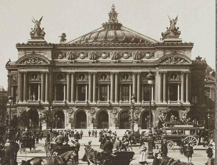 Historic American architecture with ornate details, busy street scene with horse-drawn carriages.