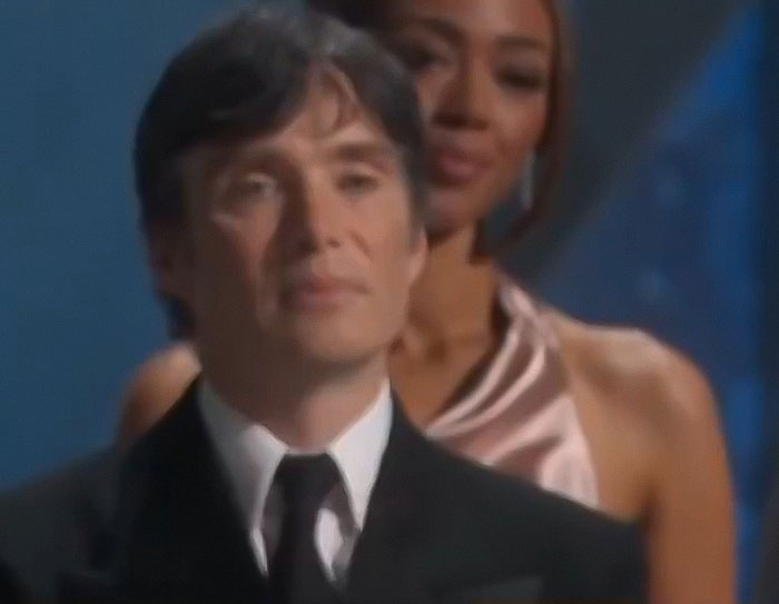 Cillian Murphy at the Oscars, expression going viral during Adrien Brody's speech, wearing a suit in a formal setting. Cillian Murphy at the Oscars, expression going viral during Adrien Brody's speech, wearing a suit in a formal setting.